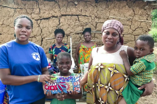 "Women helping earn in the Ghana Sewing Project proudly display their handmade garments, symbolizing their newfound financial independence achieved through microfinance initiatives."
